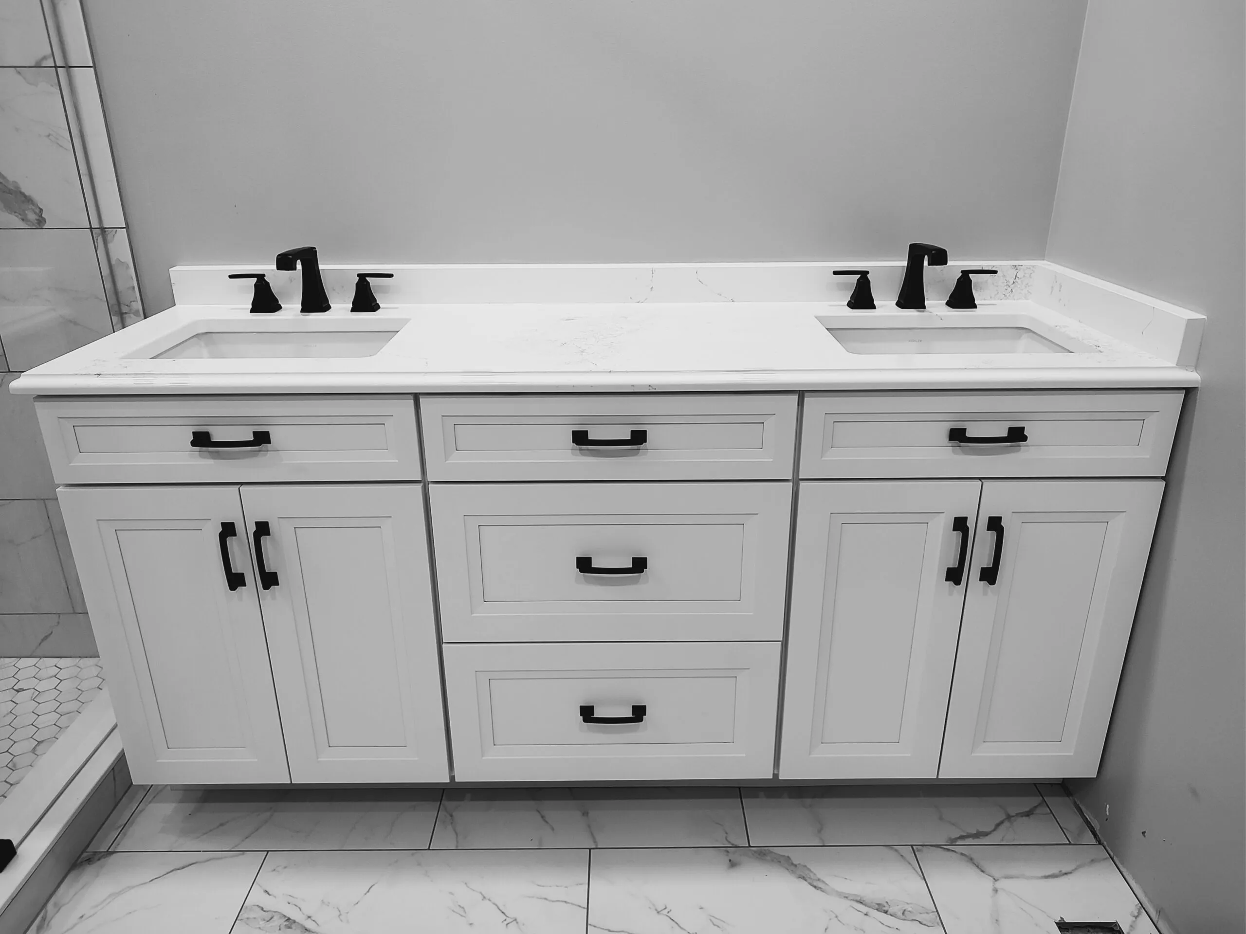 Double vanity with two undermount sinks, black faucets and marble look tile